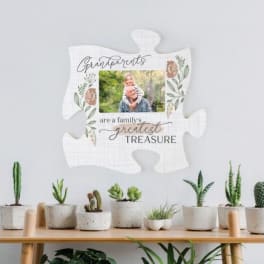 Decorative puzzle-piece sign with a family photo and potted succulents below