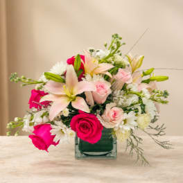 Pink and white mixed flower arrangement in a square glass vase