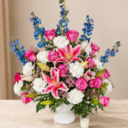 Pink roses, white lilies, and blue flowers in a white vase