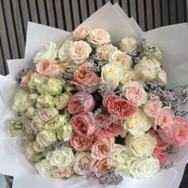Large bouquet of pastel roses with purple filler flowers in white wrap