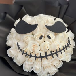 White rose bouquet wrapped in black paper with a skull face design