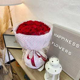 Bouquet of red roses wrapped in white heart-patterned paper