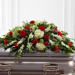 Red roses and white flowers arranged on a silver casket