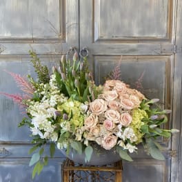 Large pastel floral arrangement with roses, tulips, and hydrangeas in a gray bowl