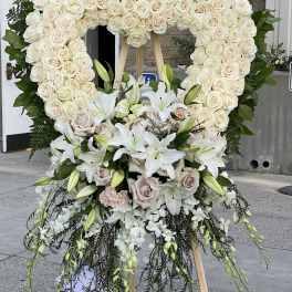 Large white floral standing heart on an easel with lilies and roses