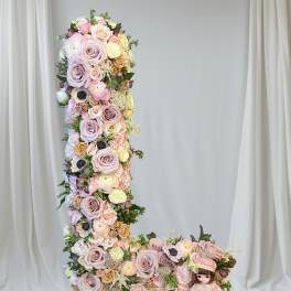 Tall floral letter L with pastel roses and a doll at the base