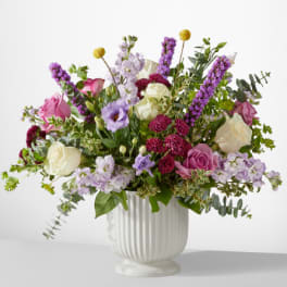 Mixed bouquet of pink, white, and lavender flowers in a white vase