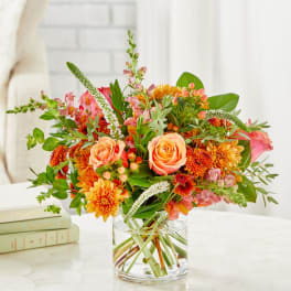 Orange and pink mixed bouquet in a clear glass vase
