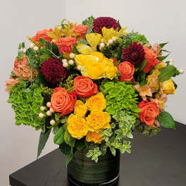 Colorful bouquet of roses, dahlias, and hydrangeas in a dark vase