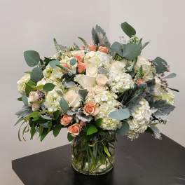Bouquet of white hydrangeas and peach roses in a glass vase