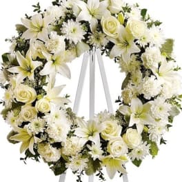 White floral wreath on a standing easel with ribbon