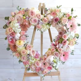 Heart-shaped floral wreath on a wooden easel with pink and white flowers