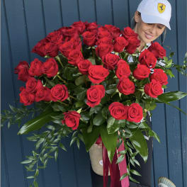 Large bouquet of red roses held by a woman in a white cap