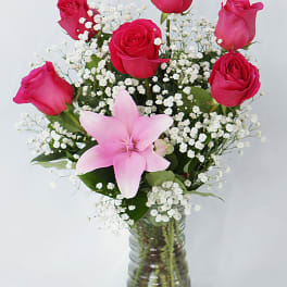 Pink roses and a lily in a glass vase with white baby's breath