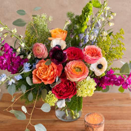 Colorful mixed bouquet in a clear glass vase with roses and anemones