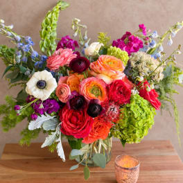 Colorful mixed bouquet in a glass vase with a candle nearby