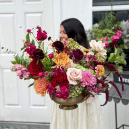 Large mixed bouquet in a brass bowl vase with pink, red, white, and purple flowers.
