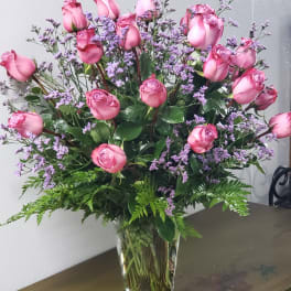 Pink roses and purple filler flowers in a clear glass vase