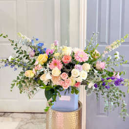 Large pastel bouquet with roses, gerbera daisies, and delphinium in a blue box