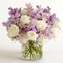 Bouquet of white roses and pink-purple flowers in a clear glass vase