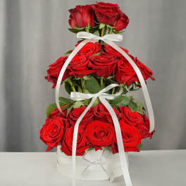 Tiered arrangement of red roses in a white box with ribbon bows
