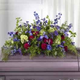 Large blue and purple floral casket spray with green foliage