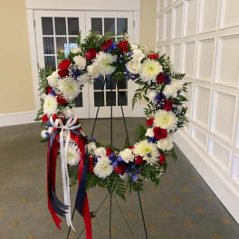 Large floral wreath on a stand with red, white, and blue flowers