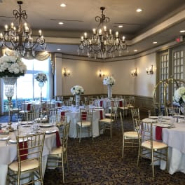 Banquet room with tall white floral centerpieces on round tables
