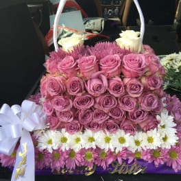 Basket arrangement of pink roses, white roses, and daisies