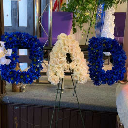 Blue floral letter wreaths and a white rose letter arrangement on stands
