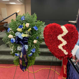 Two standing floral funeral sprays, one heart-shaped red wreath with a white crack