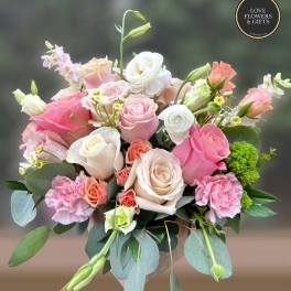 Mixed bouquet of pink and cream roses with carnations and lisianthus in a vase