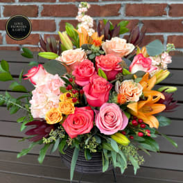Mixed bouquet of roses and lilies in a black basket vase