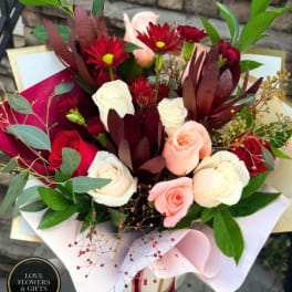 Bouquet of red, pink, and white roses with burgundy flowers and greenery