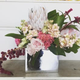 Pink and cream floral arrangement in a mirrored square vase