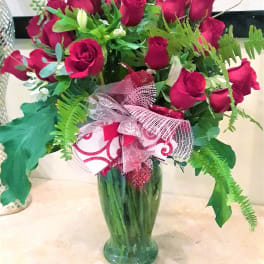 Bouquet of red roses in a green glass vase with a pink ribbon