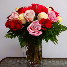 Bouquet of red, pink, and cream roses in a clear glass vase