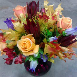 Bouquet of multicolored roses and tropical flowers in a dark vase