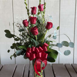 Red roses in a clear glass vase with a red ribbon