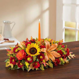 Autumn floral centerpiece with a lit orange taper candle