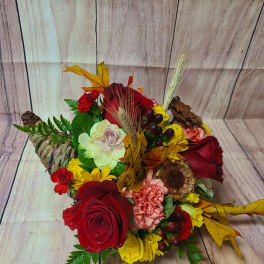 Mixed bouquet of red, yellow, and pink flowers in a woven basket