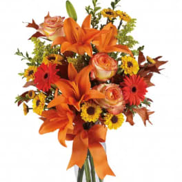 Orange lilies and mixed flowers in a vase with a ribbon