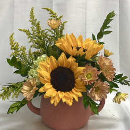 Sunflower arrangement in a terracotta mug with peach daisies