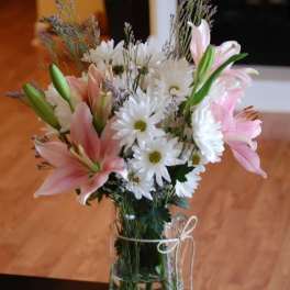 Pink lilies and white daisies arranged in a clear glass vase