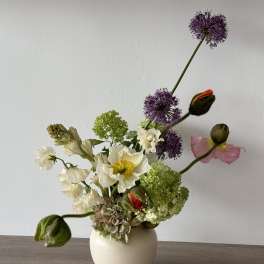White vase arrangement with white, green, purple, and pink flowers