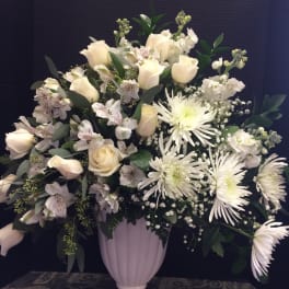 White roses and chrysanthemums arranged in a pale pedestal vase