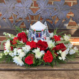 Red roses and white flowers arranged around a small holiday gazebo centerpiece