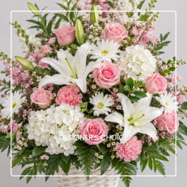 Pink roses and white lilies in a white basket with mixed blooms