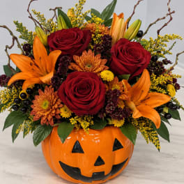 Halloween pumpkin container filled with red roses, orange lilies, and mums