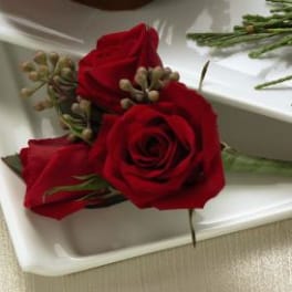 Three red rose boutonnieres on a white tray